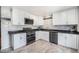 Bright kitchen featuring white cabinets, black countertop, stainless appliances, and wood-look floors at 11744 W 71St Pl, Arvada, CO 80004