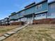 Blue townhouse exterior with a covered entrance, steps leading up, and a small front yard at 12032 Leyden St, Brighton, CO 80602