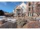 A condo building with a stone facade with private balconies and a landscaped yard with scattered snow at 19049 E Warren Dr # 105, Aurora, CO 80013
