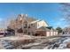 An exterior view of condo building with stone facade, multiple units and garage parking in a wintry environment at 19049 E Warren Dr # 105, Aurora, CO 80013