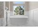 Bright, white bathroom featuring a large, modern soaking tub under a window overlooking greenery at 1658 Glade Gulch Rd, Castle Rock, CO 80104
