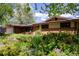 Well-maintained ranch-style home with a mix of brick and siding, nestled among trees and foliage at 962 S Beech St, Lakewood, CO 80228