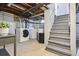 Unfinished basement area with laundry machines, stairs, and exposed ceiling at 3946 Perry St, Denver, CO 80212