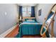 Cozy bedroom showcasing hardwood floors, a large window, and a teal quilt bedspread at 3946 Perry St, Denver, CO 80212