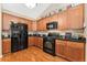 Updated kitchen featuring wood cabinets, black appliances, granite countertops, and hardwood floors at 8595 Gold Peak Dr # A, Highlands Ranch, CO 80130