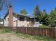 Charming home featuring a brick chimney, wooden fence, and lush landscaping at 1251 Lee St, Lakewood, CO 80215