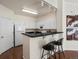 Well-lit kitchen features modern white cabinetry, black countertop with bar and stools, and stainless steel appliances at 12335 E 2Nd Dr, Aurora, CO 80011