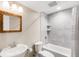 Updated bathroom featuring a tub with gray tile surround, modern fixtures, and a wood-framed mirror at 5674 S Ingalls St, Littleton, CO 80123