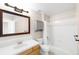 Bathroom featuring a shower over the bath, a light wood cabinet, and a matching framed mirror at 5674 S Ingalls St, Littleton, CO 80123