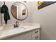 Stylish powder room with a modern sink, round mirror, and neutral wall color at 5489 Country Club Dr, Larkspur, CO 80118