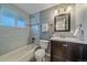 Updated bathroom with light blue walls, tile flooring, and a shower-tub combo at 6482 S Cedar St, Littleton, CO 80120
