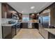 Well-lit kitchen with stainless steel appliances, tile floors, and dark wood cabinets at 6482 S Cedar St, Littleton, CO 80120