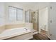Bathroom featuring a tub, a glass enclosed shower, and wood-look flooring at 179 N Prairie Falcon Pkwy, Brighton, CO 80601