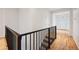 View of the staircase featuring a dark railing and view of the entry hallway at 179 N Prairie Falcon Pkwy, Brighton, CO 80601