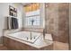 Corner bathtub features tile surround, shower and window at 18340 W 85Th Dr, Arvada, CO 80007
