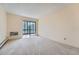 Neutral carpeted room with sliding glass doors that lead to a balcony and a wall AC unit at 14001 E Marina Dr # 211, Aurora, CO 80014