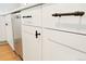 Detailed view of white kitchen cabinetry with matte black hardware and stainless steel dishwasher at 6087 S Elizabeth Way, Centennial, CO 80121