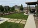 Professionally landscaped backyard featuring a covered patio, lush lawn, and charming retaining walls with mature trees at 27234 E Quarto Ave, Aurora, CO 80016