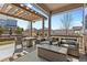 Covered outdoor patio featuring seating, a table, and a view of the manicured lawn and landscaping at 27234 E Quarto Ave, Aurora, CO 80016