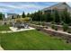 Relaxing backyard space with lush lawn, mature trees, retaining walls, and a patio area with comfortable seating at 27234 E Quarto Ave, Aurora, CO 80016