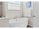 Relaxing bathroom showcasing a standalone soaking tub, window, and white color palette with neutral flooring at 27234 E Quarto Ave, Aurora, CO 80016