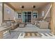 Covered patio with brick accents, comfortable seating, and a sliding glass door entrance at 27234 E Quarto Ave, Aurora, CO 80016