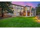 Beautifully landscaped backyard, with lush lawn, featuring a deck and a covered patio area at 22554 Treetop Ln, Golden, CO 80401