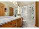 Traditional-style bathroom with white tile, wood cabinetry, and shower-tub combo at 22554 Treetop Ln, Golden, CO 80401