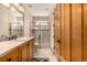 Well-lit bathroom with wood cabinets, tiled shower, and a modern design at 22554 Treetop Ln, Golden, CO 80401