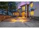Elegant home exterior with stone accents, mature trees, and pathway lighting leading to the front door at 22554 Treetop Ln, Golden, CO 80401