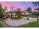 Elegant home with a three car garage, stone accents, mature trees, and a beautifully lit driveway at dusk at 22554 Treetop Ln, Golden, CO 80401