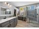 Bright bathroom featuring double vanity, walk-in glass shower, and ample natural light from multiple windows at 15 Amaranth Dr, Littleton, CO 80127