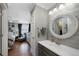 Cozy bathroom adjacent to a bedroom featuring a round mirror, a sink, and paneled wall at 15 Amaranth Dr, Littleton, CO 80127