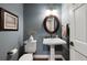 Charming half bathroom featuring a pedestal sink, oval mirror, soft lighting, and clean, modern fixtures at 15 Amaranth Dr, Littleton, CO 80127