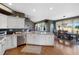 Open kitchen featuring an island sink, stainless appliances, granite countertops and an adjacent dining and living area at 15 Amaranth Dr, Littleton, CO 80127