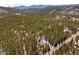Stunning aerial view of a home nestled among towering pine trees with distant mountain views at 400 Upper Forest Rd, Idaho Springs, CO 80452
