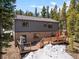 The beautiful home features a spacious wooden deck in a treed lot partially covered in snow at 400 Upper Forest Rd, Idaho Springs, CO 80452