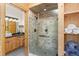 Well-lit bathroom with wood cabinets, glass shower, and a neatly organized towel shelf at 400 Upper Forest Rd, Idaho Springs, CO 80452