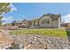 Expansive backyard boasts a patio with seating and lounge chairs, complemented by lush grass and landscaping at 15137 W 50Th Pl, Golden, CO 80403