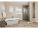 Luxurious main bathroom featuring a freestanding tub, a frameless glass shower, and stylish stone tile at 15137 W 50Th Pl, Golden, CO 80403