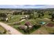Aerial view of ranch-style home with horse property, featuring lush green pastures, mature trees, and fencing at 2464 Remington Rd, Elizabeth, CO 80107