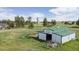 White and green barn with an open entrance, set amidst a sprawling green pasture with mature trees at 2464 Remington Rd, Elizabeth, CO 80107