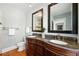 Bathroom featuring double vanity with granite counters, wood cabinets, and two framed mirrors at 1582 Steele St, Denver, CO 80206