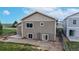 Backyard view of a tan-colored two-story home with sliding glass door, concrete patio, and fenced-in area at 169 Westin Ave, Brighton, CO 80603