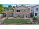 Backyard view of a tan-colored two-story home with sliding glass door, fire pit, and wood fence at 169 Westin Ave, Brighton, CO 80603
