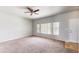 Spacious living room with carpet flooring, a ceiling fan, and large windows providing ample natural light at 169 Westin Ave, Brighton, CO 80603