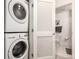 Efficient laundry closet with stacked washer and dryer, open to a bathroom with modern gray towels at 1700 Bassett St # 409, Denver, CO 80202