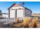 View of a garage exterior featuring a decorative stone facade, multi-car garage doors, and an American flag on a sunny day at 10883 E 163Rd Ct, Brighton, CO 80602