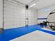 A spacious garage interior with blue flooring, white walls, and tall doors able to accommodate large vehicles at 10883 E 163Rd Ct, Brighton, CO 80602