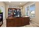 Well-lit office with a large wooden desk, built-in bookshelf, and a bright window view at 10883 E 163Rd Ct, Brighton, CO 80602